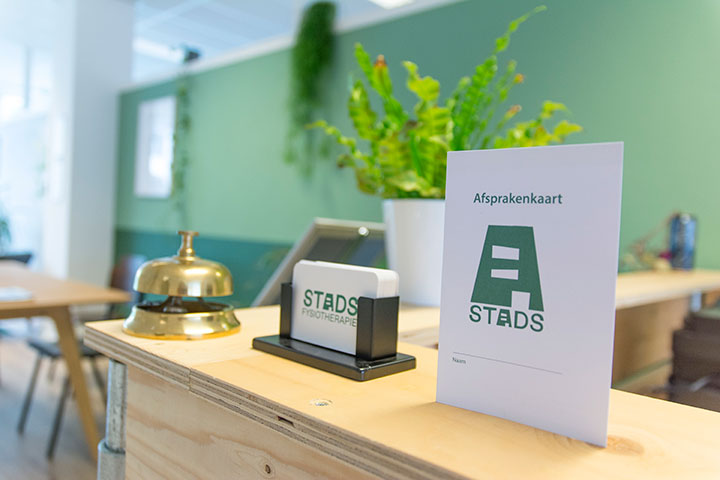 Balie met afspraakkaartjes in wachtruimte met veel daglicht en planten bij STADS Fysiotherapie