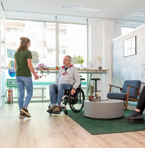 Fysiotherapeut haalt patiënt in rolstoel op uit wachtruimte bij STADS Fysiotherapie